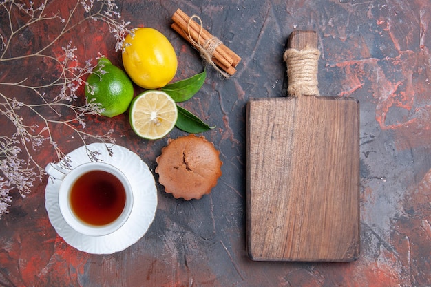 Top view citrus fruits cinnamon a cup of tea lemon lime cupcake tree branches the cutting board