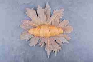Foto gratuita vista dall'alto del classico croissant francese su foglie secche