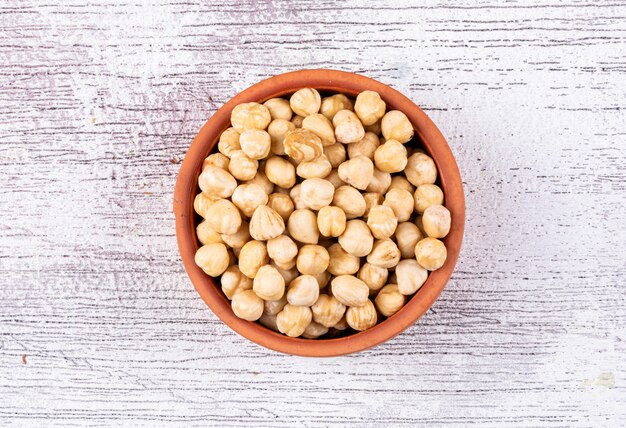 Top view cleaned hazelnuts in bowl on white wooden table. horizontal