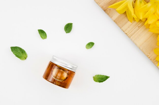 Top view close up shot jar of honey with flowers and leaves