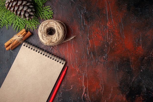 Top view of closed notebook with pen cinnamon limes a ball of rope on dark background