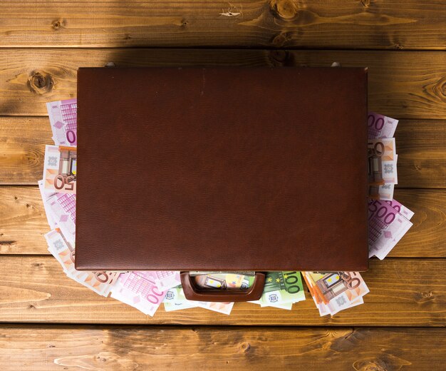 Top view closed wooden suitcase with euros