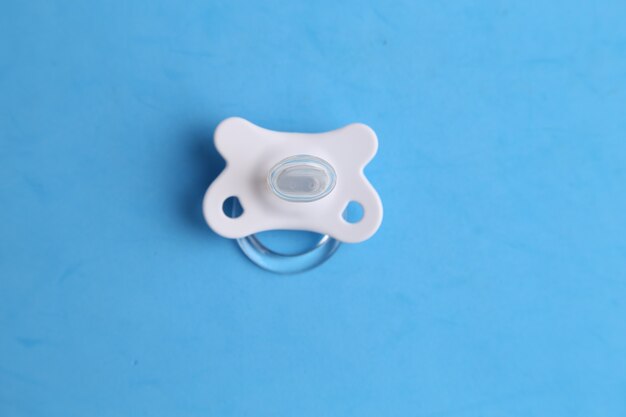Top view closeup of a pacifier of a baby used to suck upon on a blue surface