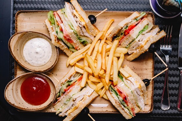 Top view of club sandwich served with french fries ketchup and mayonnaise