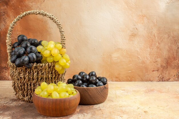 Top view of clusters of yellow and black grapes in a wooden basket and in small brown pots