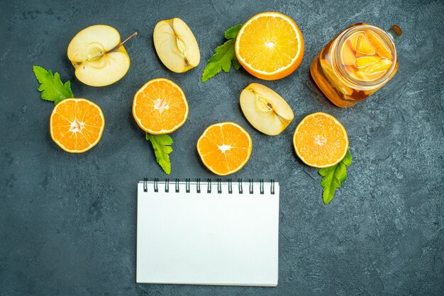 Top view cocktail cut oranges and apples on dark isolated background