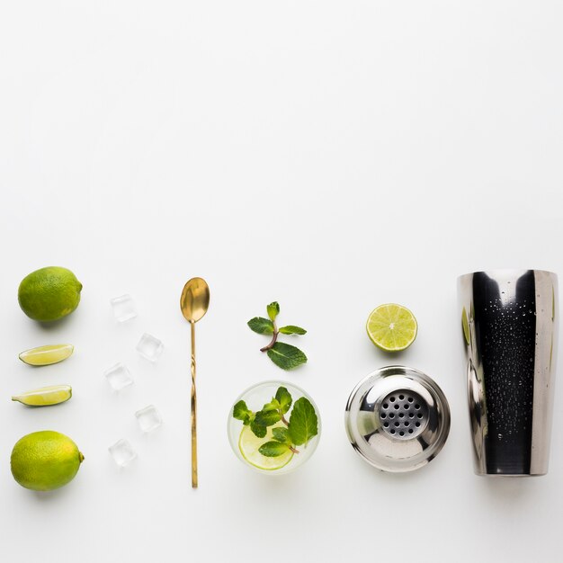 Top view of cocktail essentials with shaker and lime