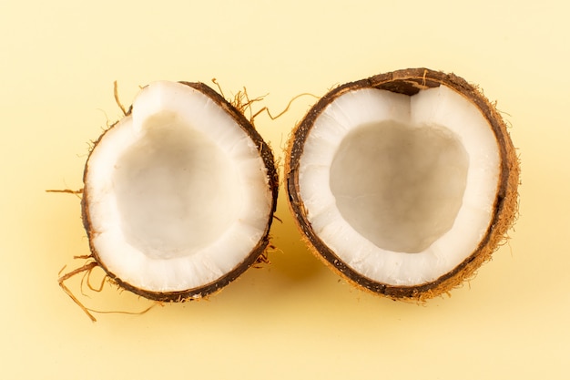 Вид сверху кокосовых орехов нарезанный молочно-свежей спелой, изолированных на кремовом фоне тропического экзотического фруктового ореха