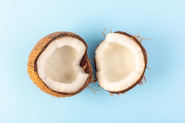 Вид сверху на кокосовые орехи нарезанный молочно-свежей спелой, изолированный на ледяной синий
