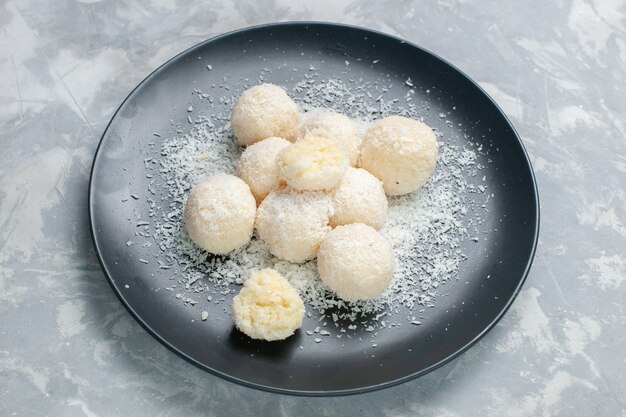 Top view coconut candies inside plate on light