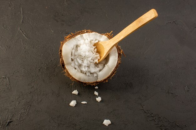 A top view coconut fruit half cut with wooden spoon inside its pulp on the grey background fruit exotic milk