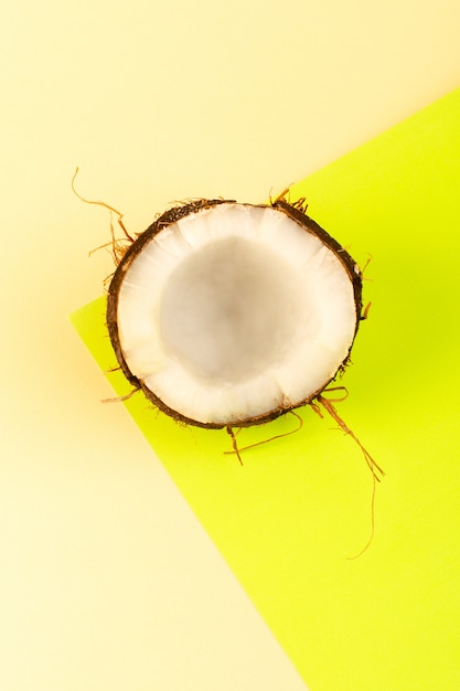 Free photo a top view coconuts whole and sliced milky fresh mellow isolated on the cream-yellow colored