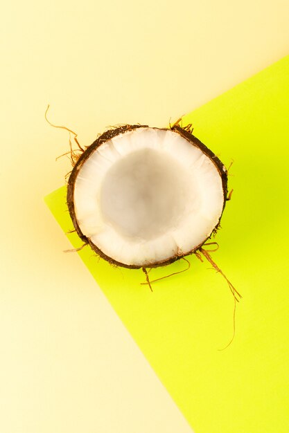 A top view coconuts whole and sliced milky fresh mellow isolated on the cream-yellow colored