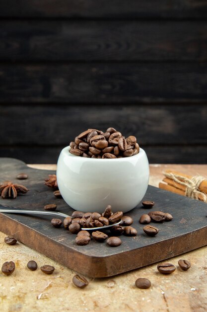 혼합 색상 배경의 나무 판자에 있는 작은 흰색 그릇 내부와 외부의 커피 콩의 상위 뷰