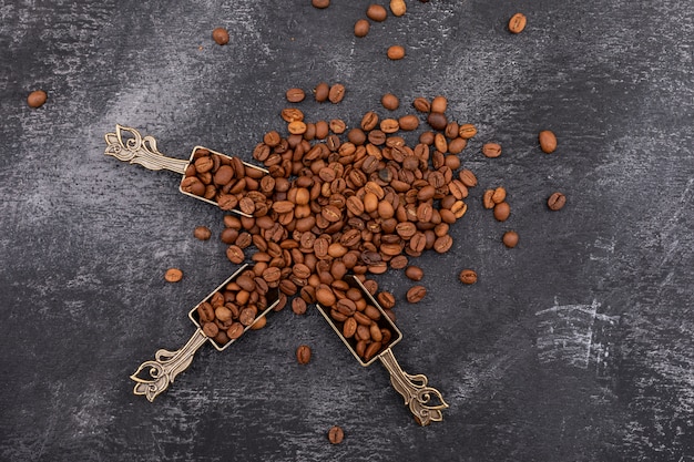 кофе в зернах сверху в металлической ложке на темной поверхности