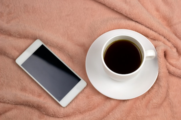 Чашка кофе сверху и сотовый телефон на розовом одеяле Premium Фотографии