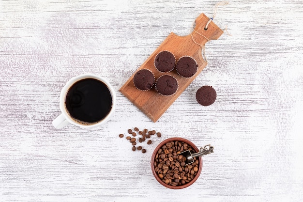 Top view coffee cup with coffee beans and chocolate muffins on white table