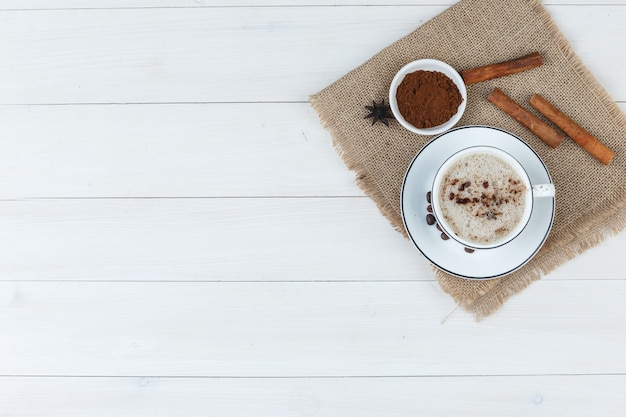 コーヒー豆、挽いたコーヒー、木製のスパイスと袋の背景とカップのトップビューコーヒー。水平