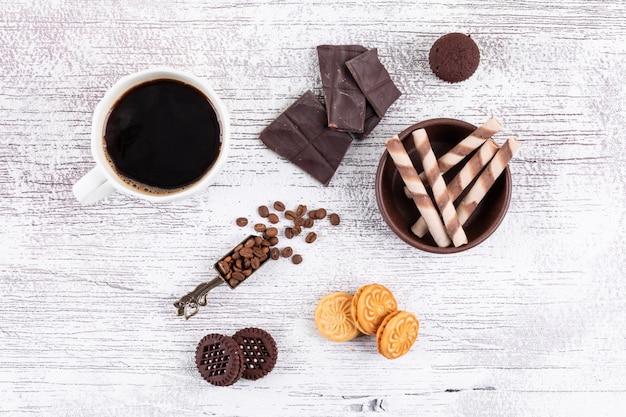 Top view coffee cup with cookies and chocolate on white table