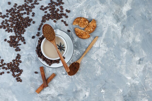 Top view coffee in cup with cookies, coffee beans, grinded coffee, spices on grey plaster background. horizontal