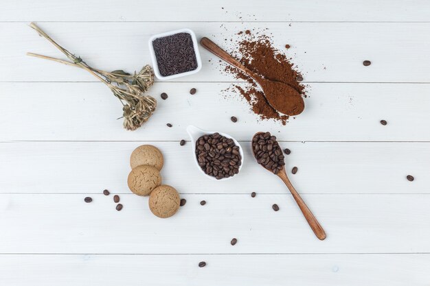 Top view coffee in cup with grinded coffee, coffee beans, dried herbs, cookies on wooden background. horizontal