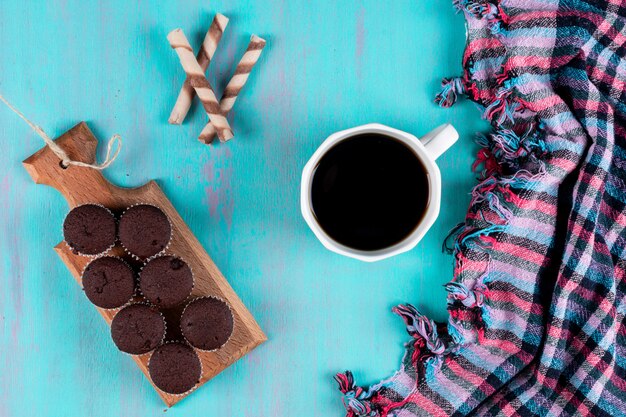 top view coffee cup with muffins on wooden board on blue surface