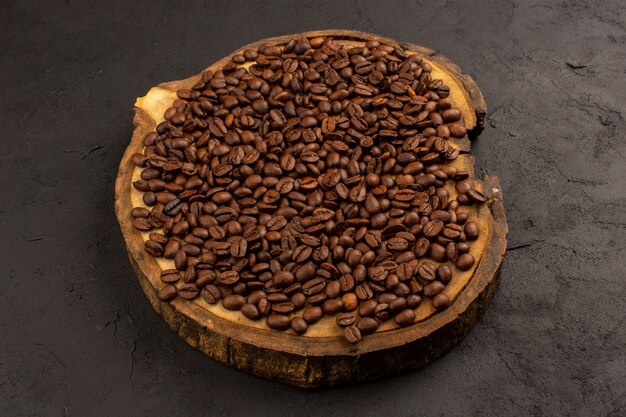 茶色の机と暗い床に茶色の全体のコーヒー豆の上面図