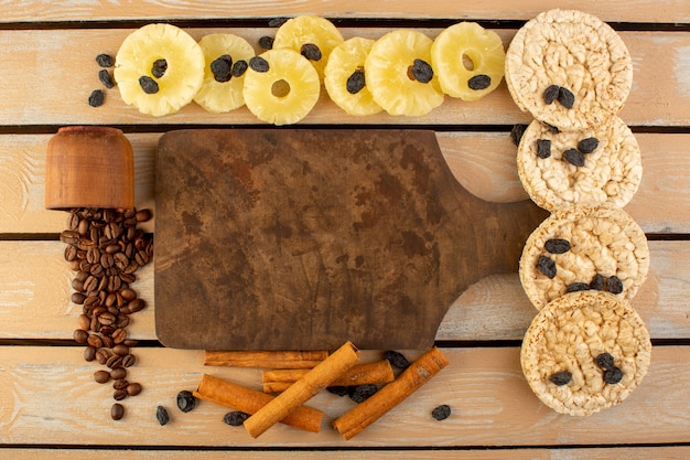 Foto gratuita una vista dall'alto di semi di caffè con ananas essiccato cannella da tavola e cracker sul tavolo rustico crema di semi di caffè bevanda foto grano