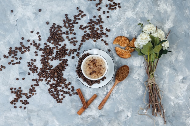 grinded 커피, 커피 콩, 꽃, 계피 스틱, 지저분한 회색 배경에 쿠키와 상위 뷰 커피. 수평