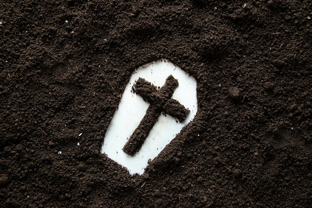 Top view of coffin shape with cross and brown soil