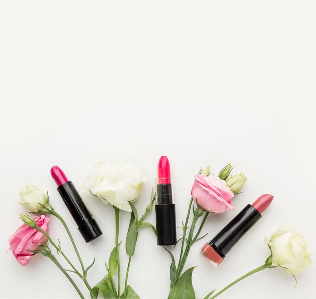 Top view collection of lipstick and flowers with copy space