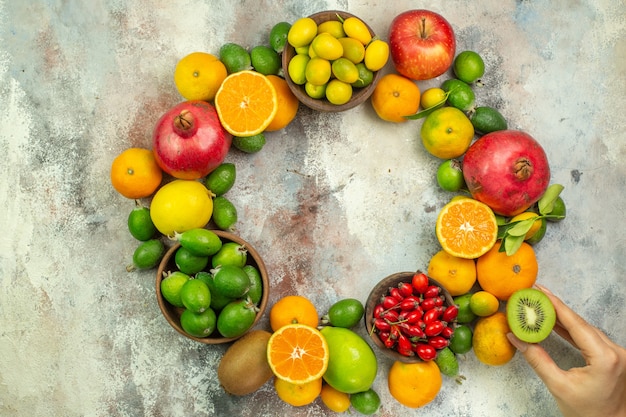 混合色の背景に全体とカットの新鮮な果物のコレクションの上面図