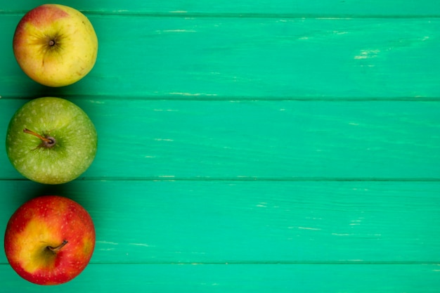 Top view of colored apples on a green surface