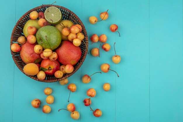 Free photo top view of colored apples with white cherries in a basket on a turquoise surface