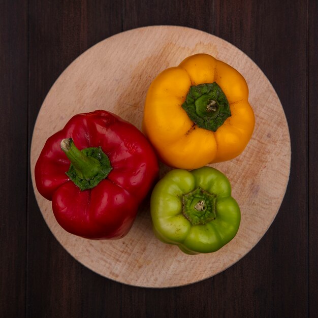 Top view colored bell peppers on cutting board  on wooden background