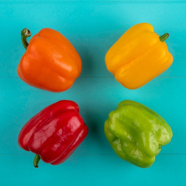 Top view of colored bell peppers on a turquoise surface