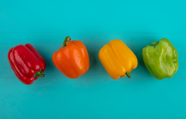 Top view of colored bell peppers on a turquoise surface