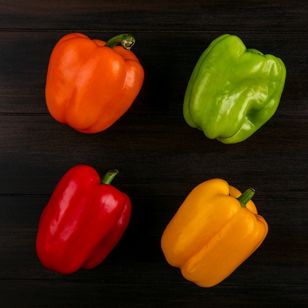 Top view of colored bell peppers on a wooden surface