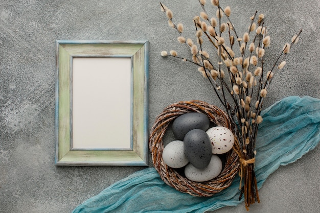 Top view of colored easter eggs in basket with twigs and frame