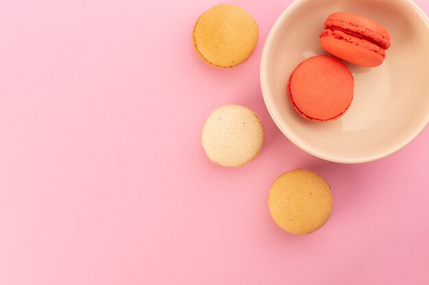 Цветные французские макароны, вид сверху, вкусные и запеченные на розовом столе, бисквит, сладкий сахар