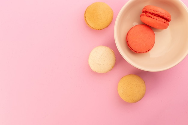 A top view colored french macarons delicious and baked on the pink desk cake biscuit sweet sugar