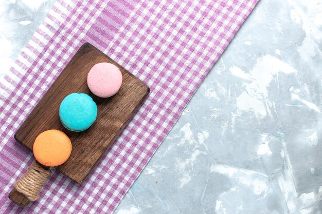 Top view colored french macarons round formed baked delicious cakes on light-white desk.