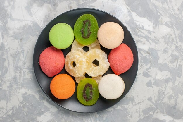 Top view colored little cakes with dried pineapple rings on light-white surface
