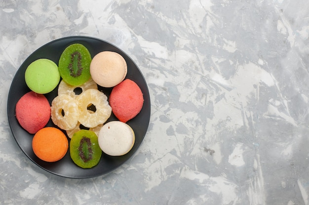 Top view colored little cakes with dried pineapple rings on light-white surface