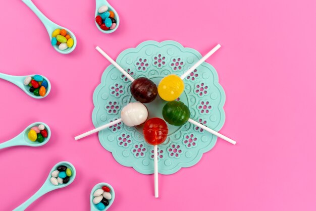 A top view colored lollipops with colorful candies on pink