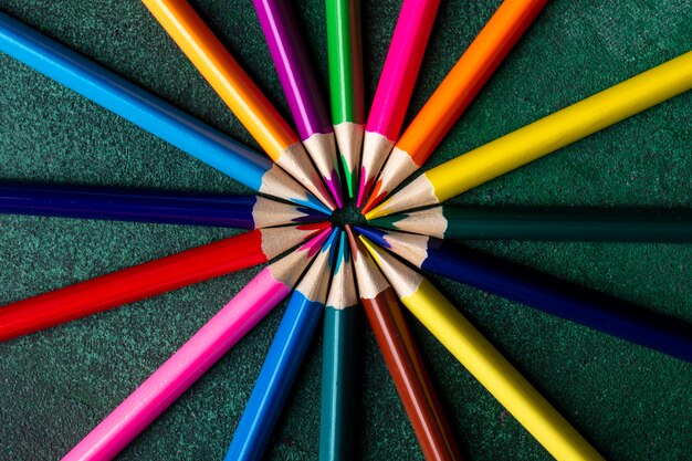 Top view of colored pencils arranged on dark