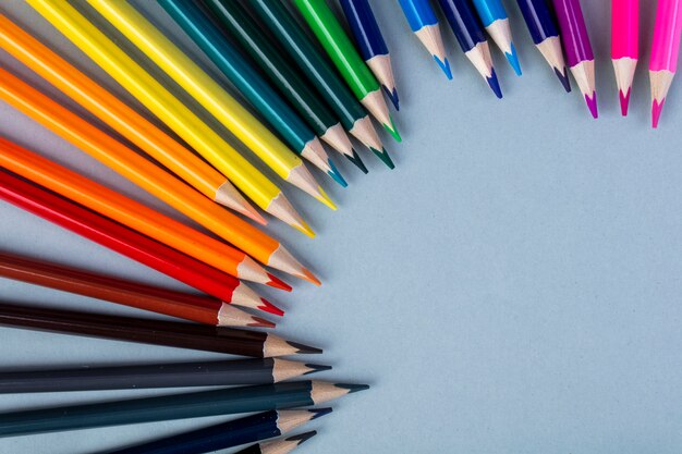 top view of colored pencils arranged on white with copy space