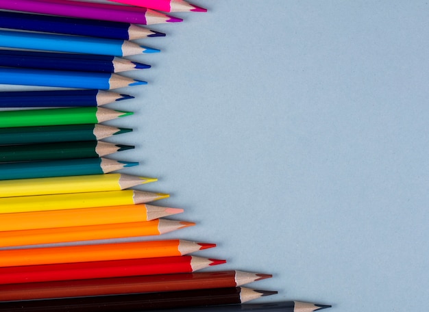 Top view of colored pencils arranged on white with copy space