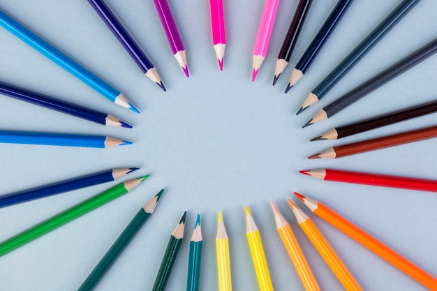 Top view of colored pencils arranged on white