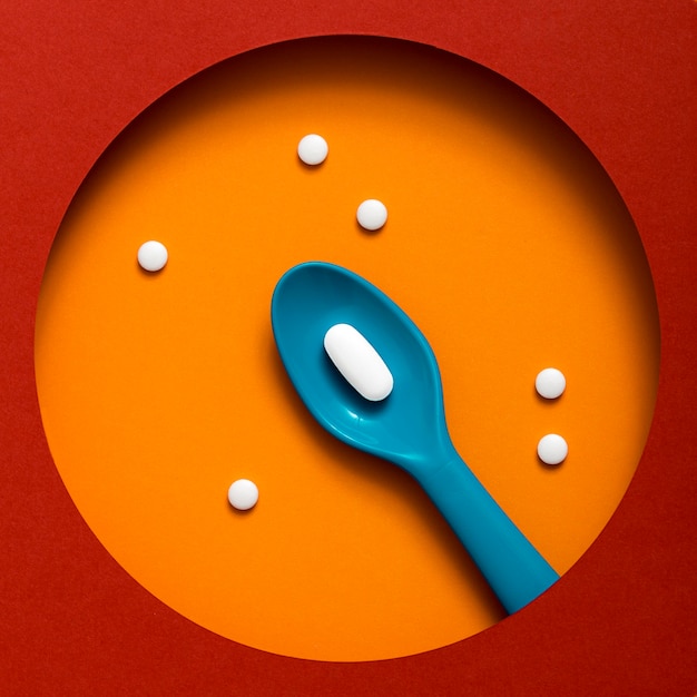 Foto gratuita vista dall'alto di un cucchiaio di plastica colorata con pillola